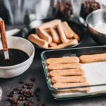 Tazza di tiramisù decorata con cacao e chicchi di caffè, pronta da gustare.